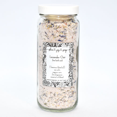 Lavender Botanical Bath Salt Soak in glass jar.  Lavender Oat Bath Soak is a gentle blend of sea salts and colloidal oats.  This best selling scent is the same lovely fragrance as our soap supreme bar “Lavender Sage” -  top notes of rosemary and thyme, heart notes of lavender and sage, and base notes of powder and musk, this essential oil fragrance oil blend is a classic clean herbaceous dream.   Skin Joy Soap Murfreesboro Tennessee